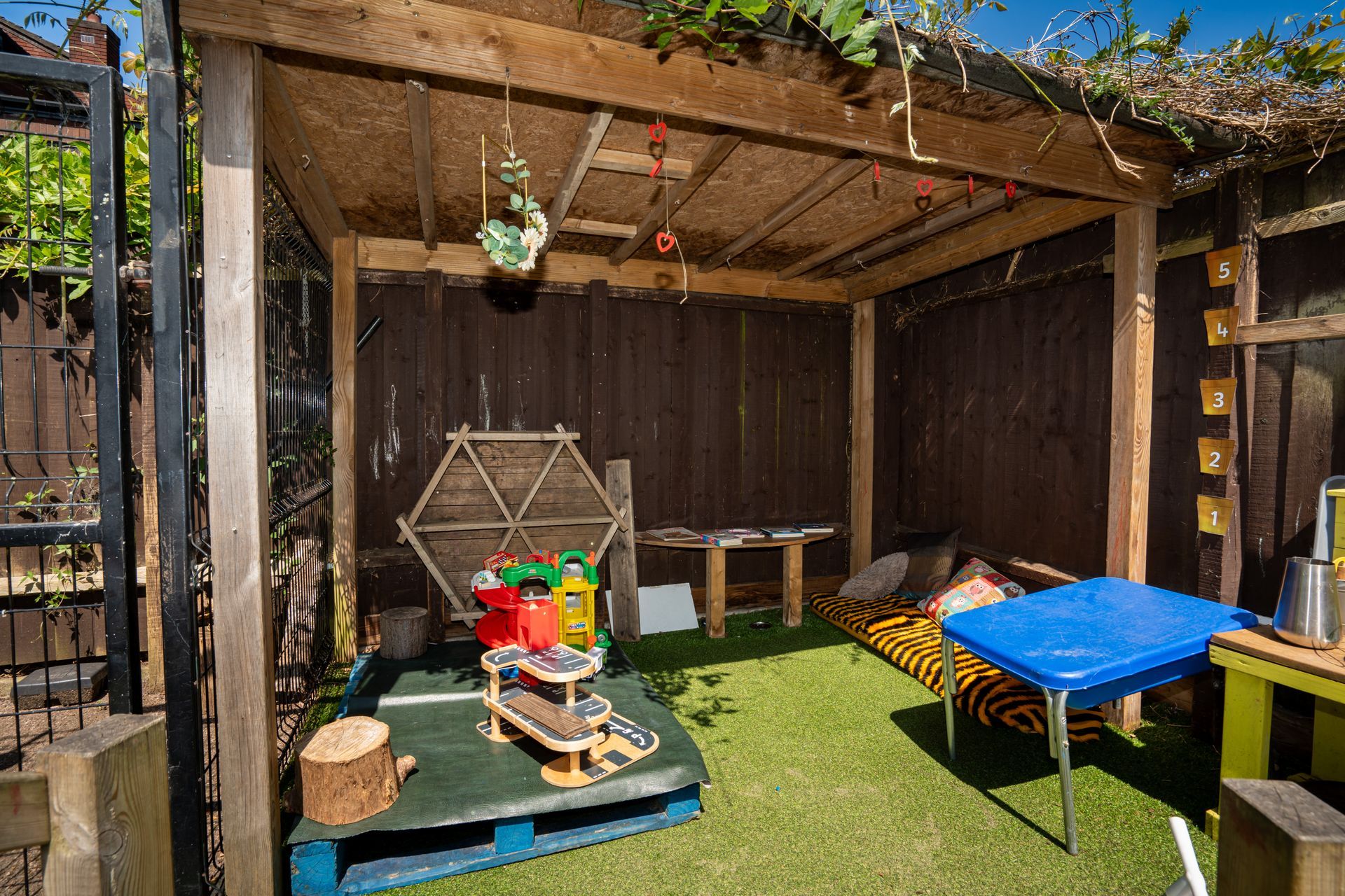 There is a table and chairs under a pergola in the backyard. Gingerbread