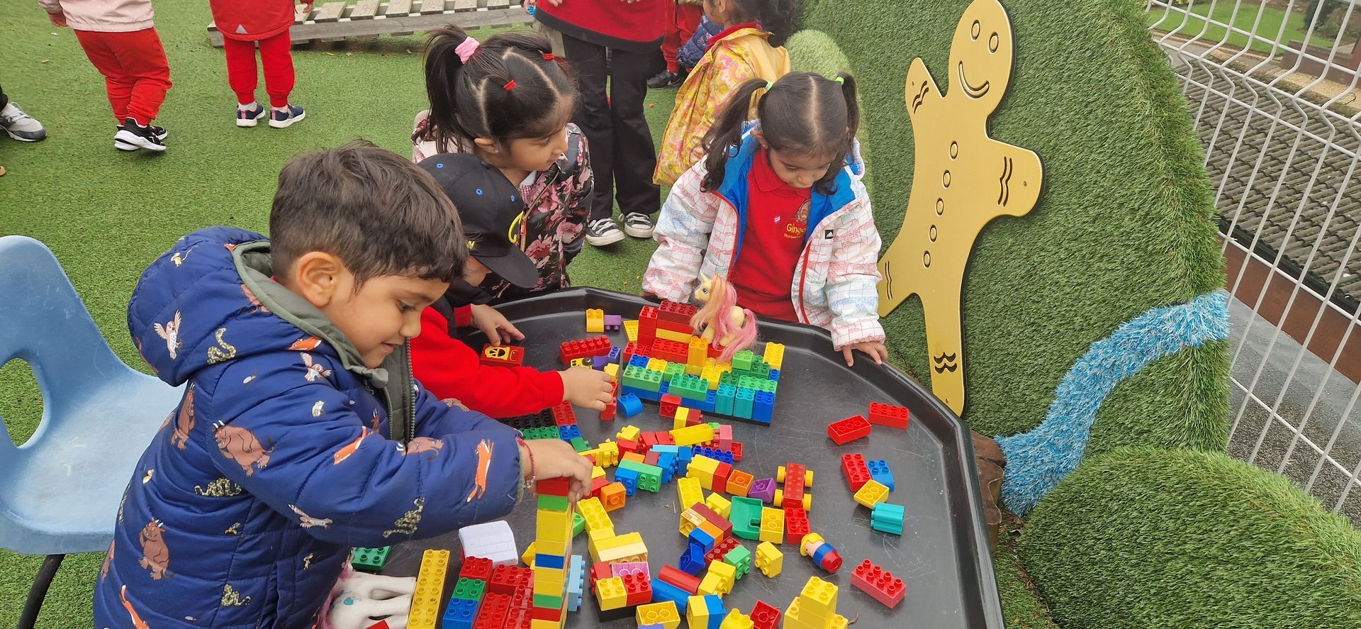 A group of children are playing with lego blocks on a table. Gingerbread