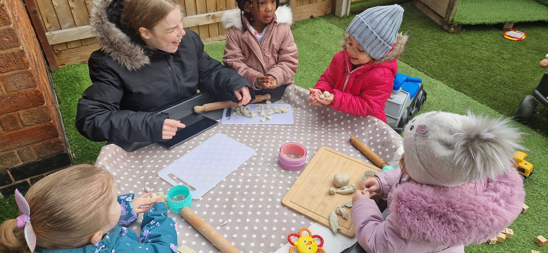 A group of children are sitting around a table playing with clay. Gingerbread