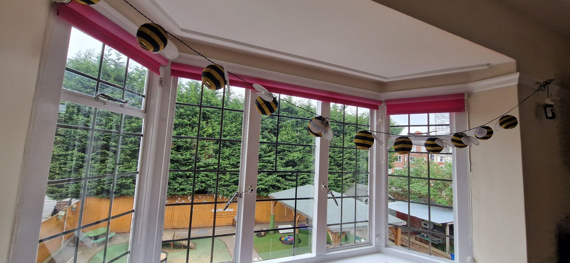 A room with a lot of windows and bees hanging from the ceiling. Gingerbread