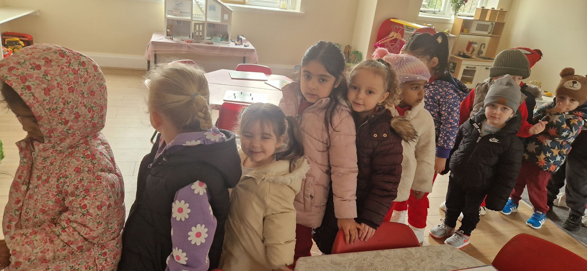 A group of children are standing in a line in a room. Gingerbread