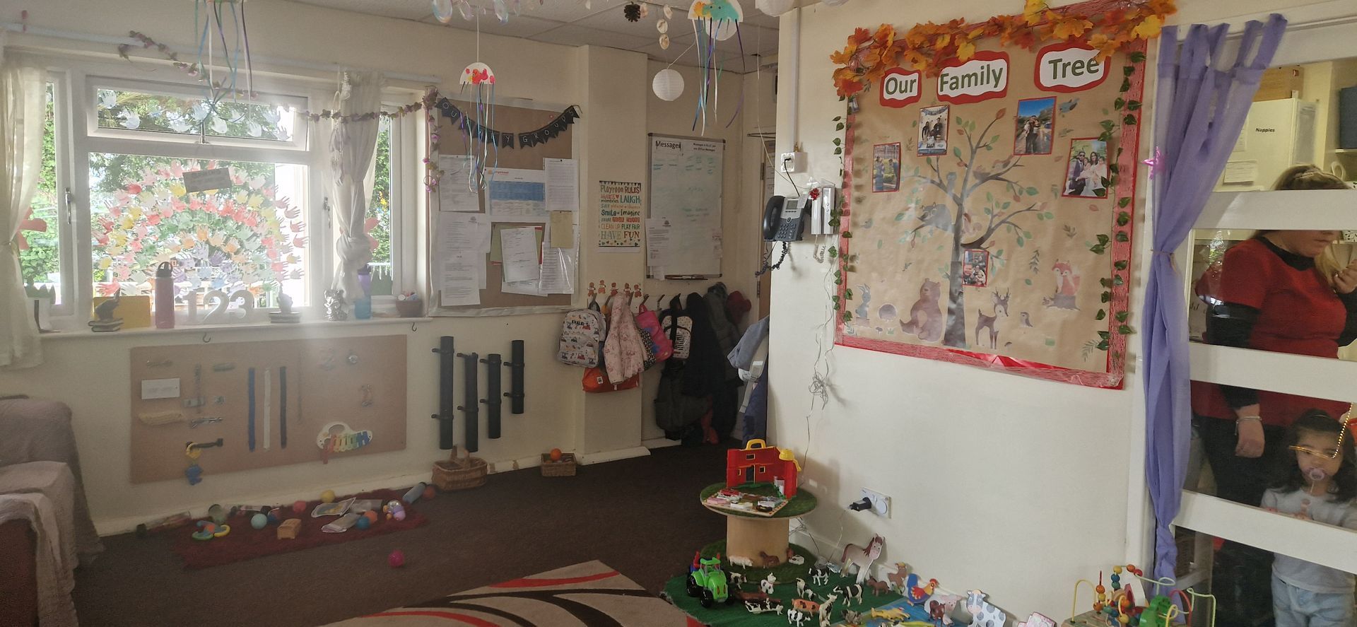 A room with a bulletin board on the wall and a rug on the floor. Gingerbread