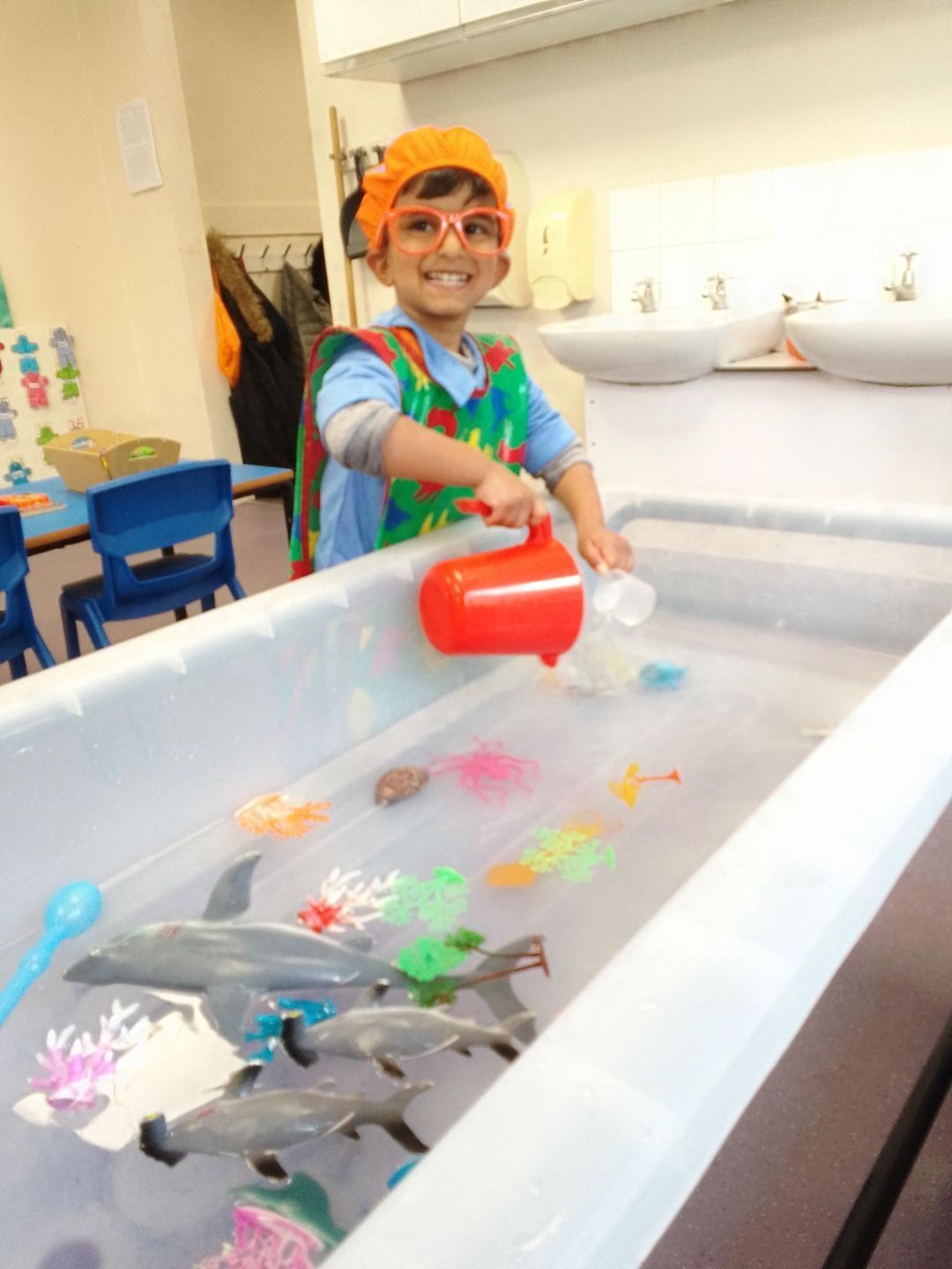 A young boy is pouring water into a tub with dolphins in it Gingerbread