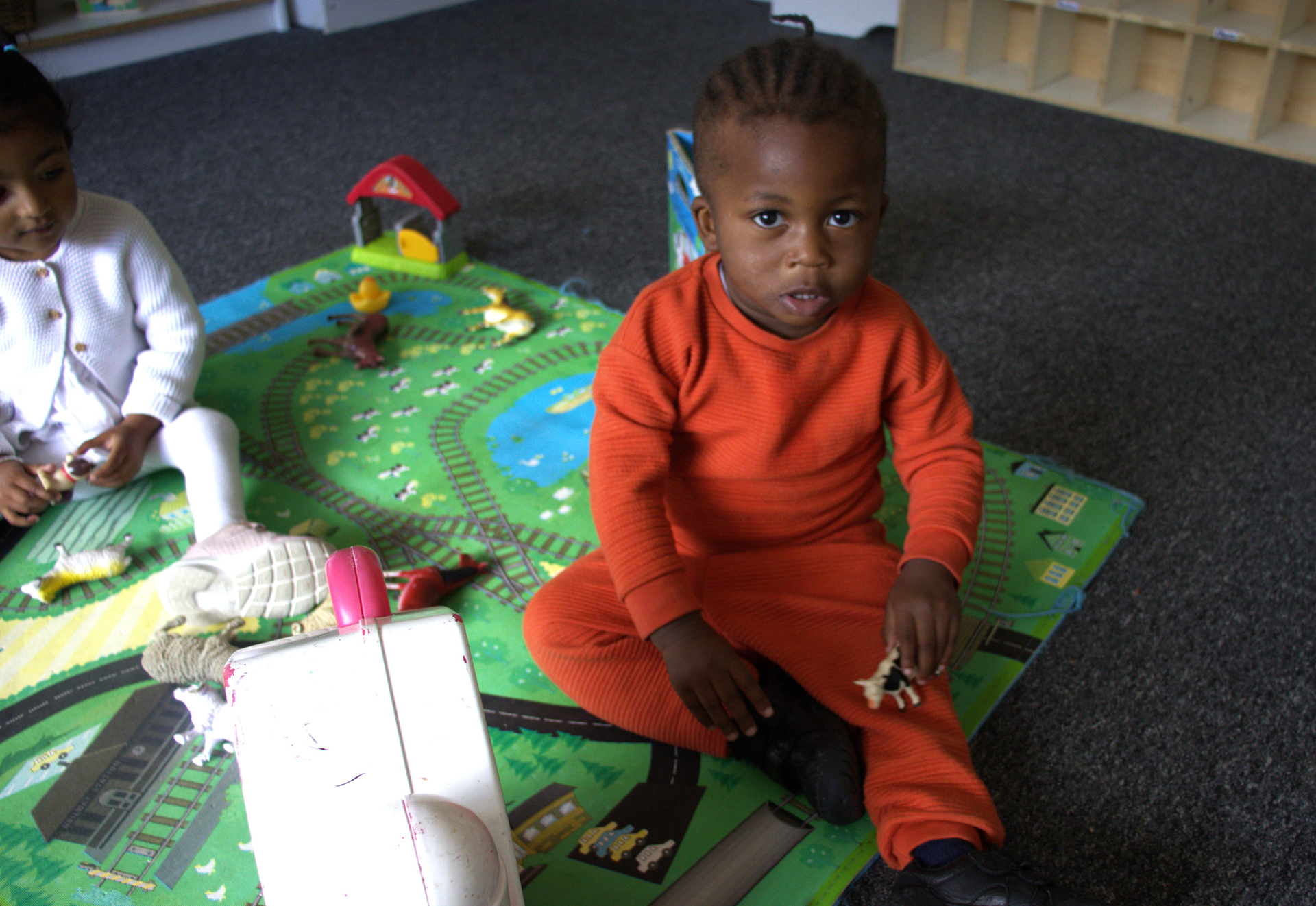 Two children are sitting on a rug playing with toys Gingerbread