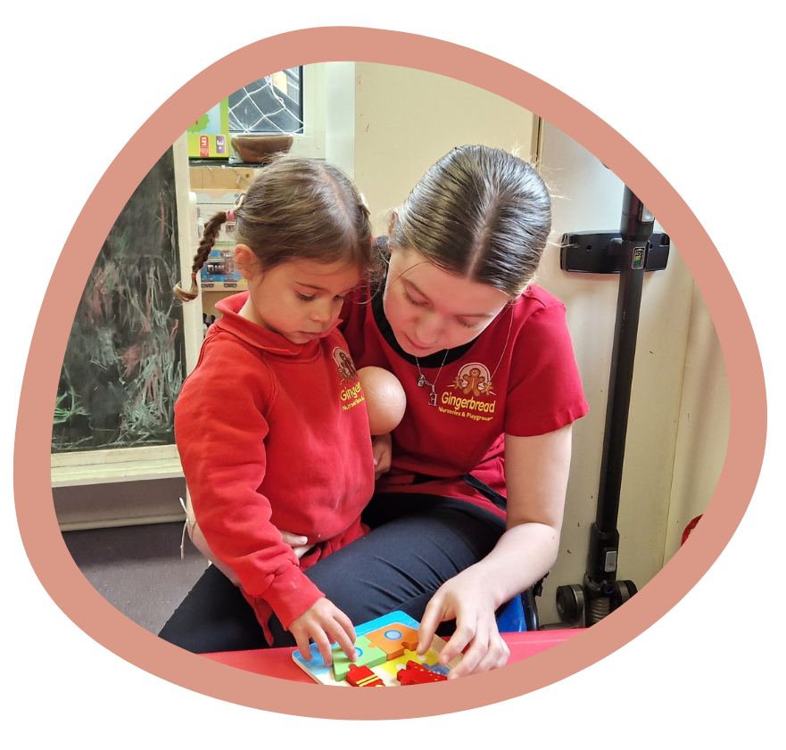 A woman is sitting next to a little girl who is playing with a puzzle. Gingerbread