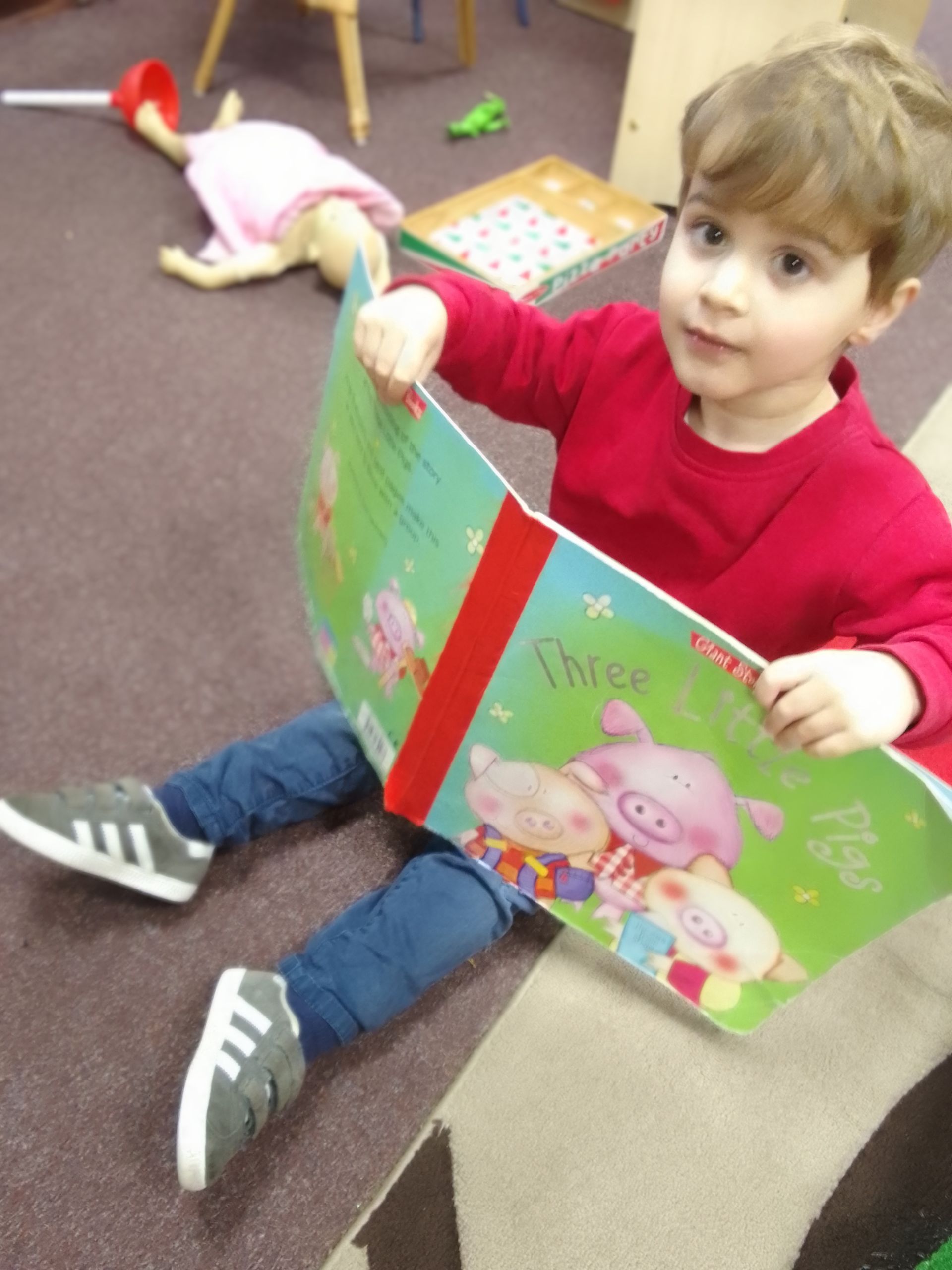 A little boy is reading a book called three little pigs Gingerbread