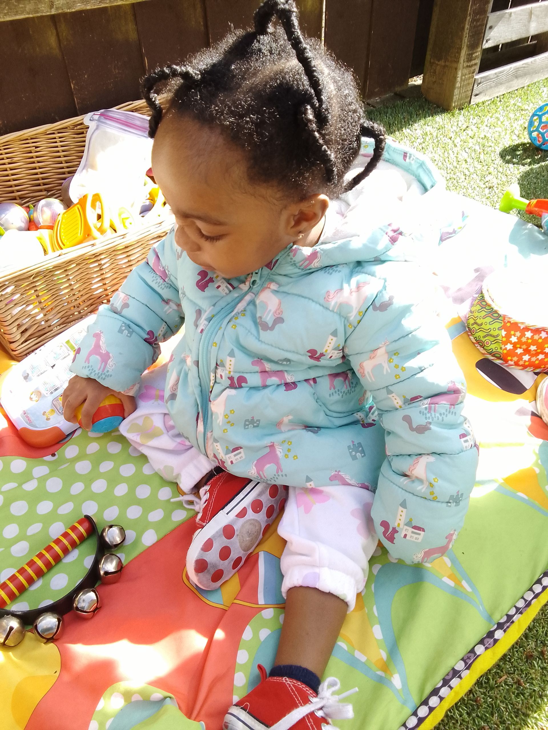 A baby is sitting on a blanket playing with toys. Gingerbread