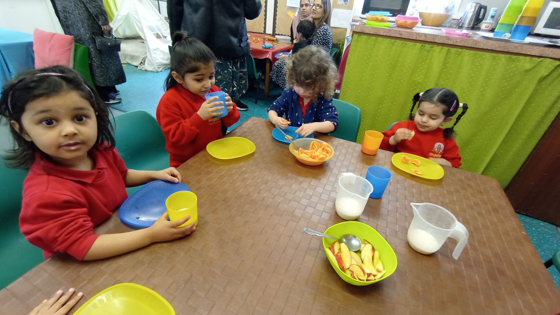 A group of children are sitting at a table eating food. Gingerbread