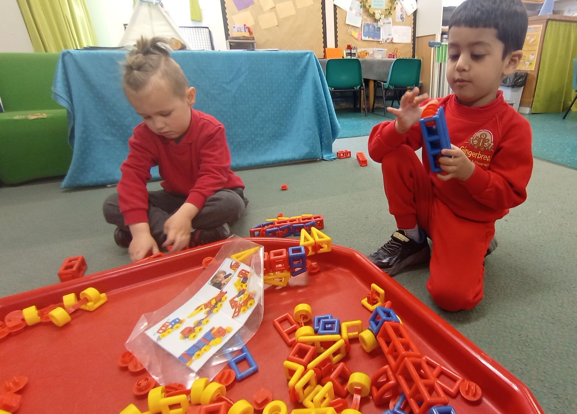 A boy and a girl are playing with lego blocks on a table. Gingerbread