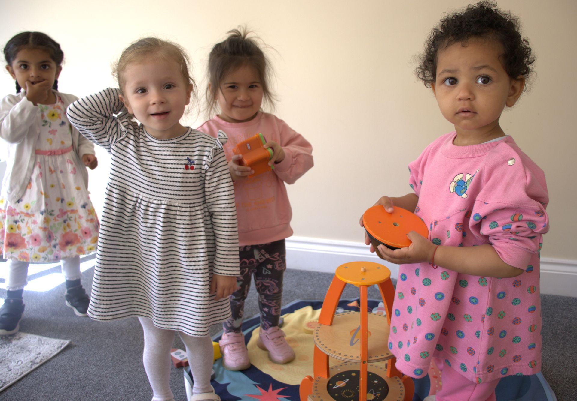 A group of young girls are standing next to each other in a room holding toys. Gingerbread