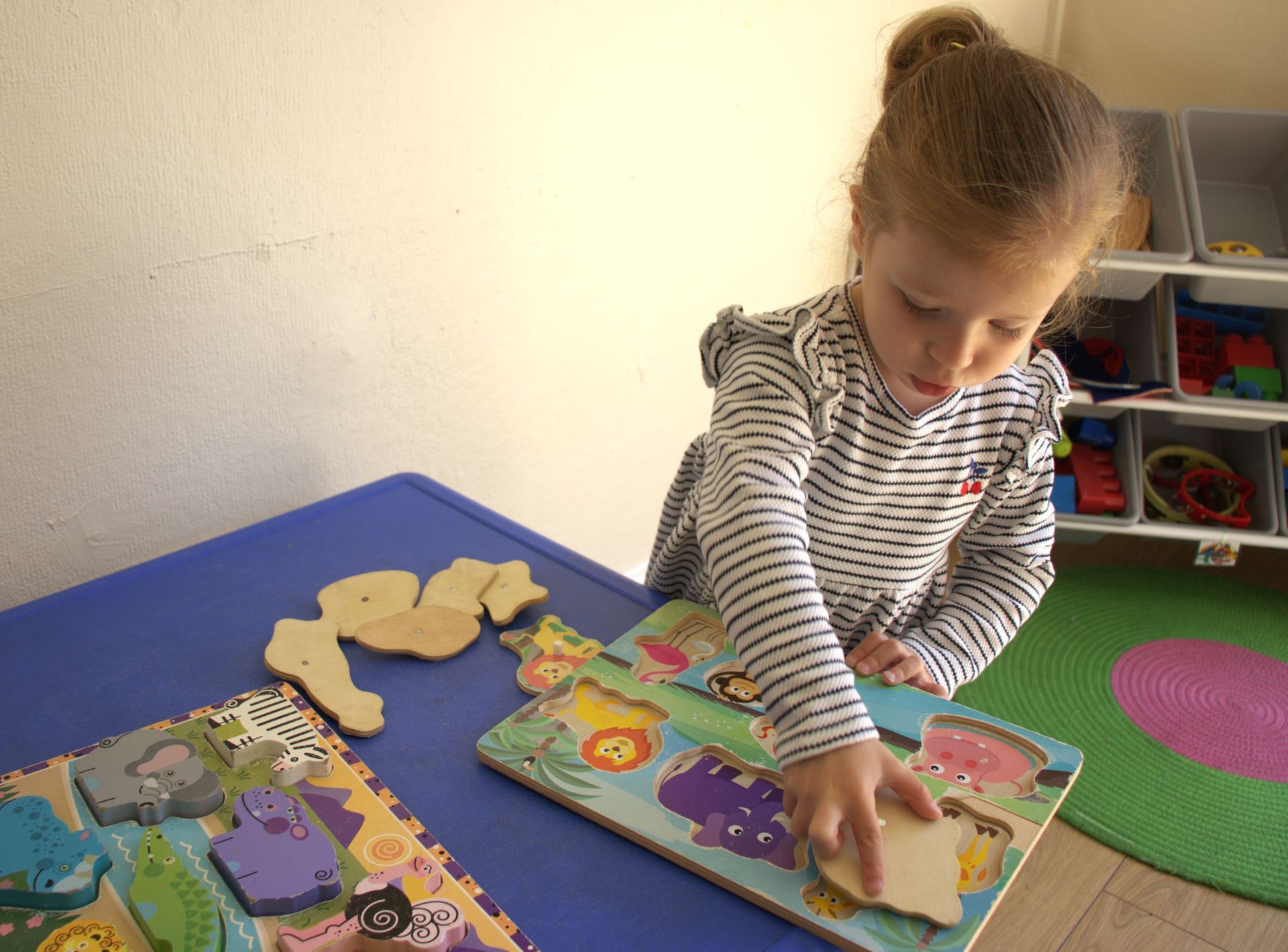 A little girl is playing with a puzzle on a table. Gingerbread