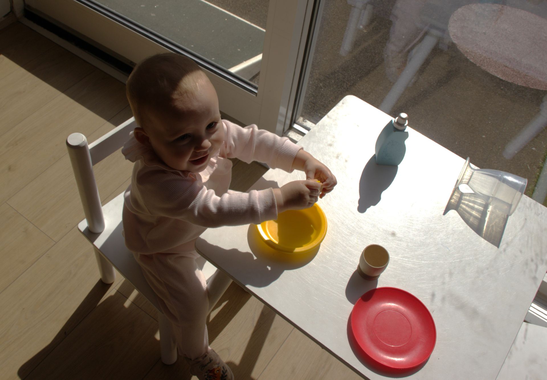 A baby is sitting at a table with a yellow bowl and a red plate Gingerbread