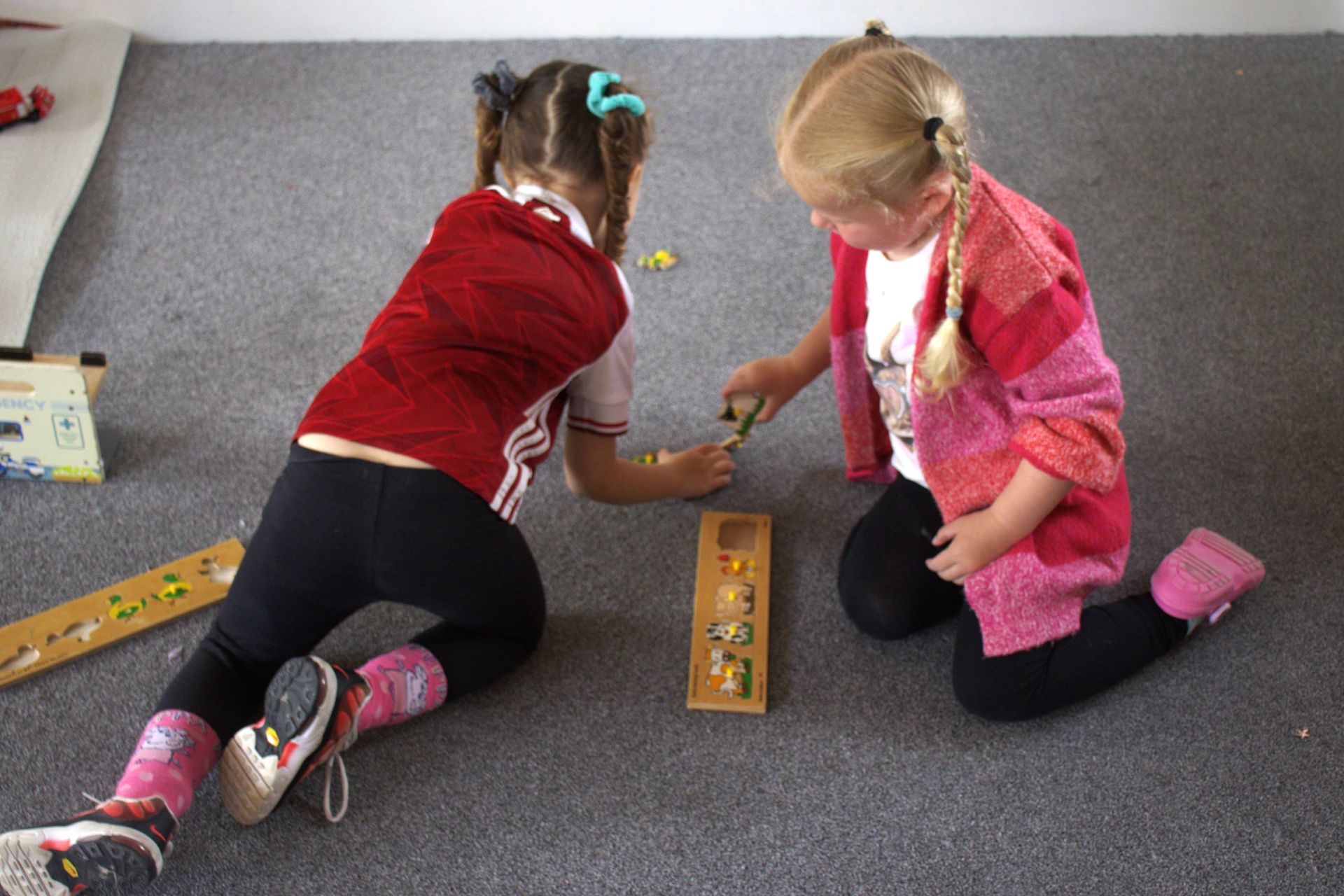 Two little girls are playing with toys on the floor Gingerbread