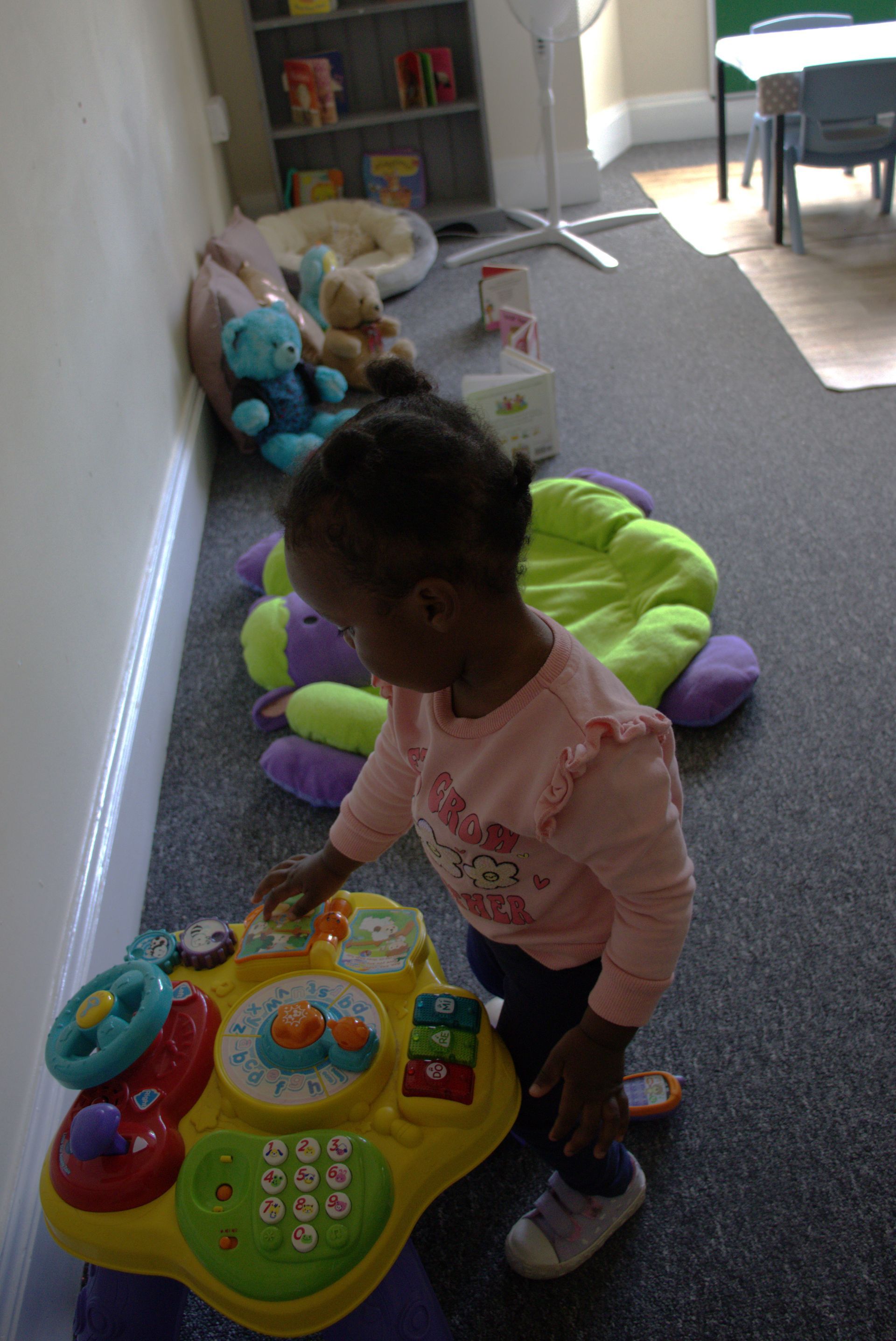 A little girl is playing with a toy in a room. Gingerbread