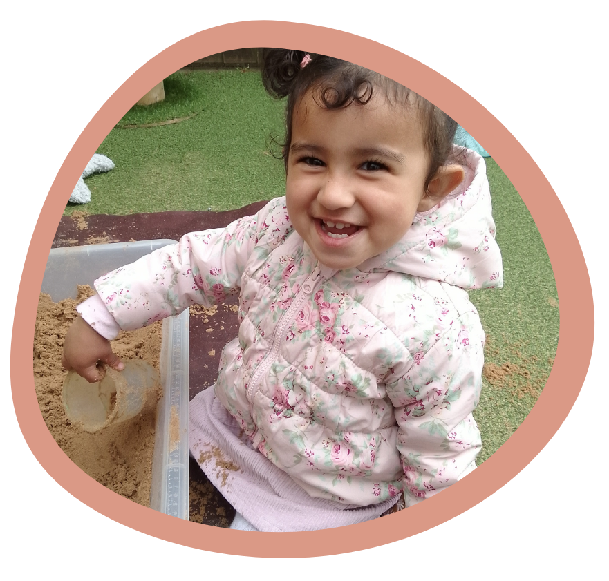 A little girl is smiling while playing in the sand Gingerbread