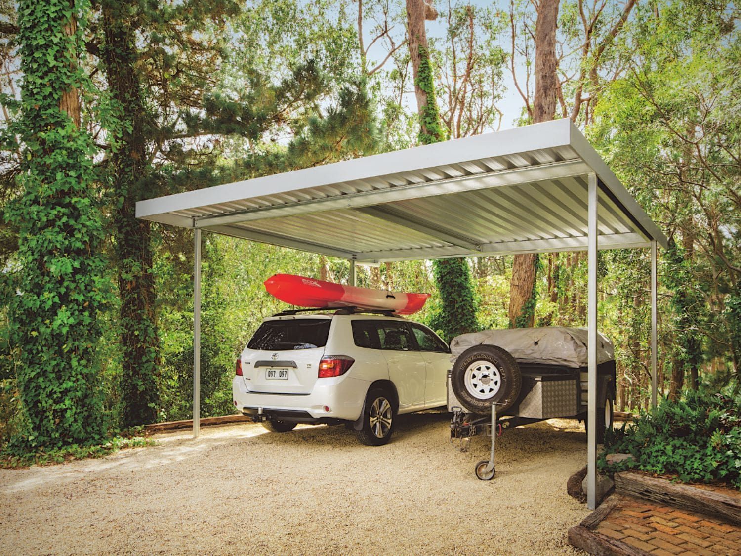 A car is parked under a canopy with a kayak on top of it.