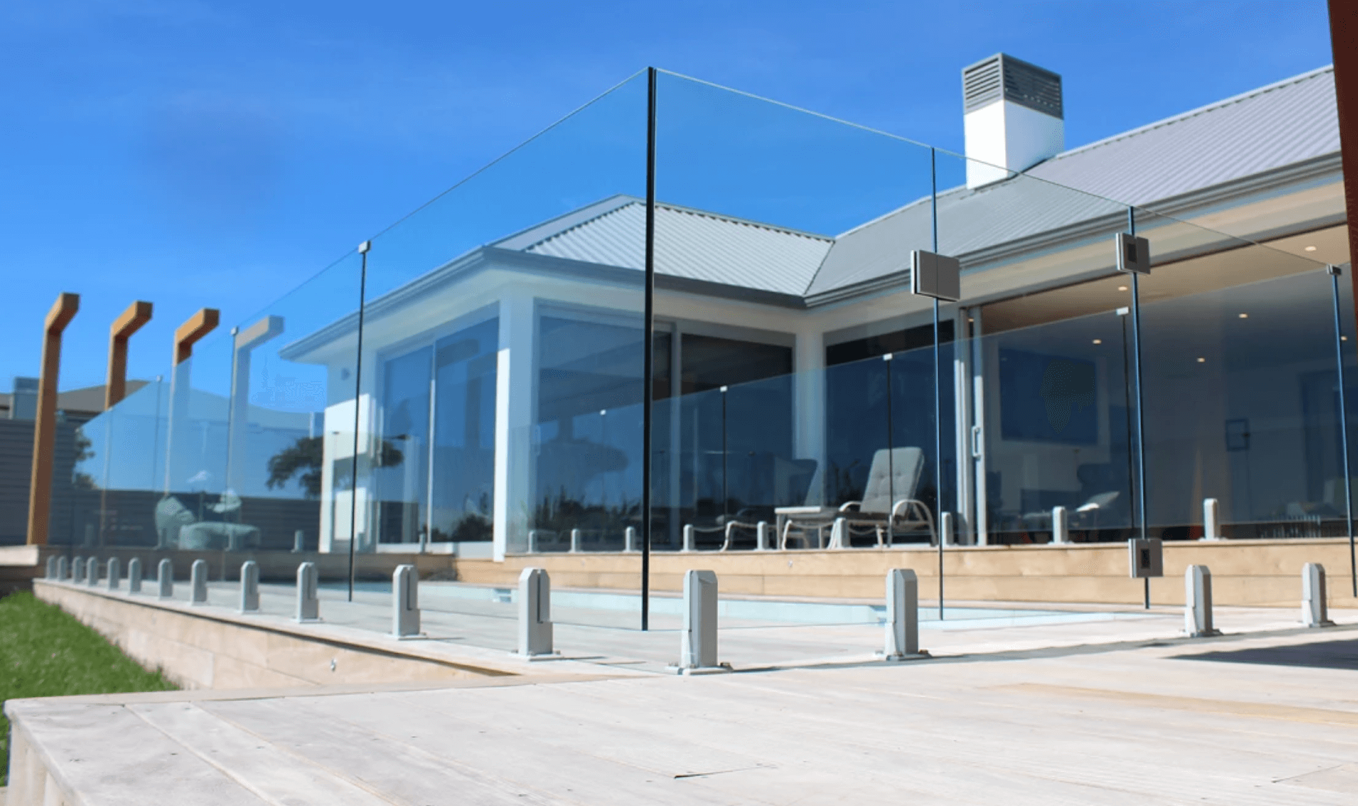 A large house with a swimming pool and a glass fence around it.