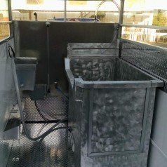 A metal container with a hose attached to it is sitting inside of a trailer.