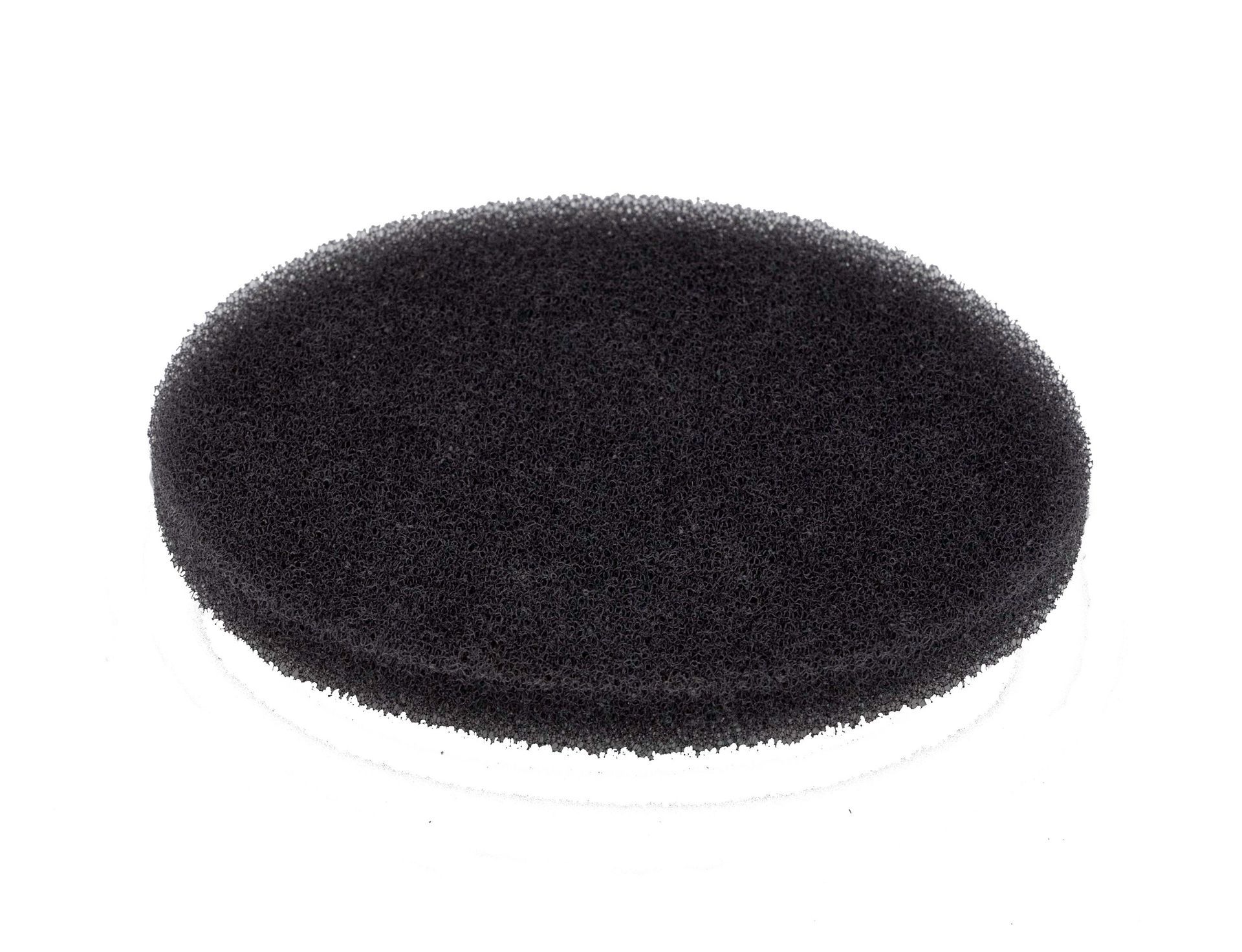 A black sponge is sitting on a white surface.