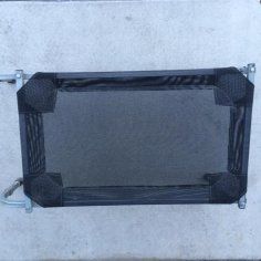 A black mesh gate is sitting on top of a concrete surface.