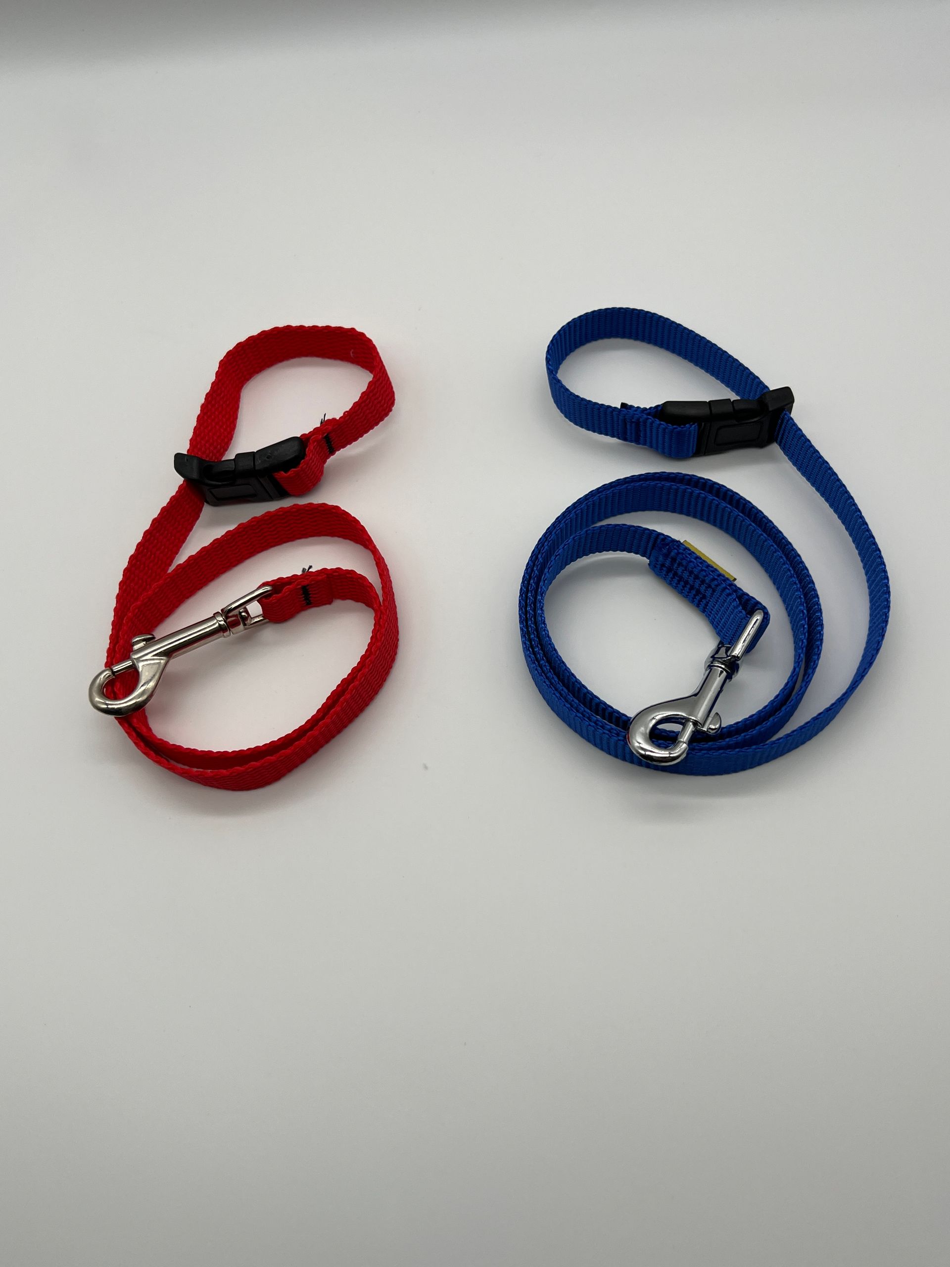 A red leash and a blue leash on a white surface