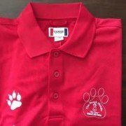 A red polo shirt with a paw print on it is sitting on a table.