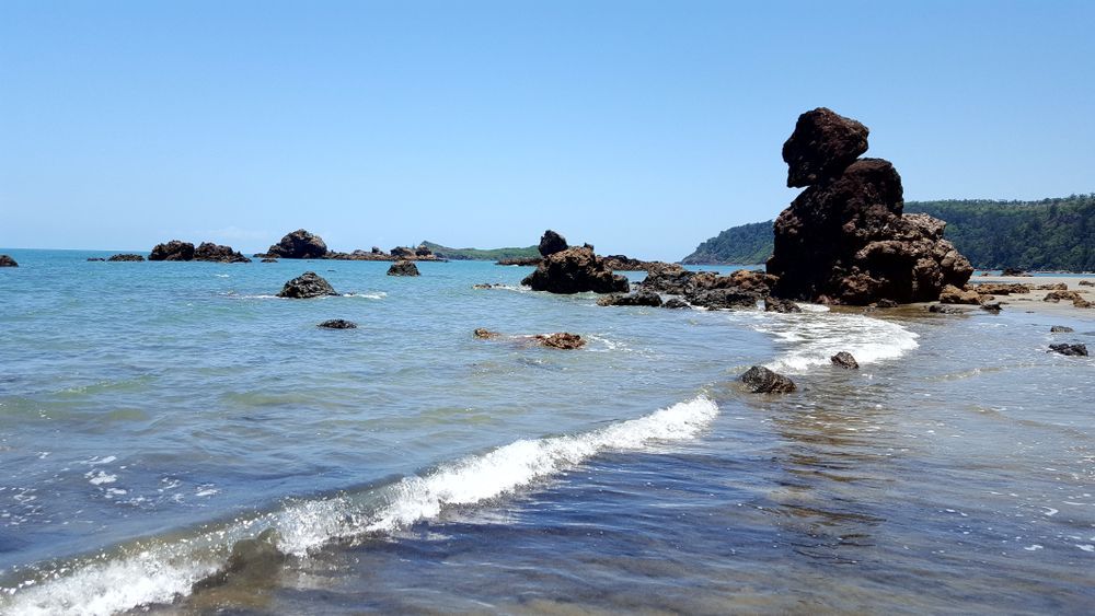 A Large Rock Is In The Middle Of The Ocean On A Beach — Australian Specialised Machinery Glass In Mackay, QLD