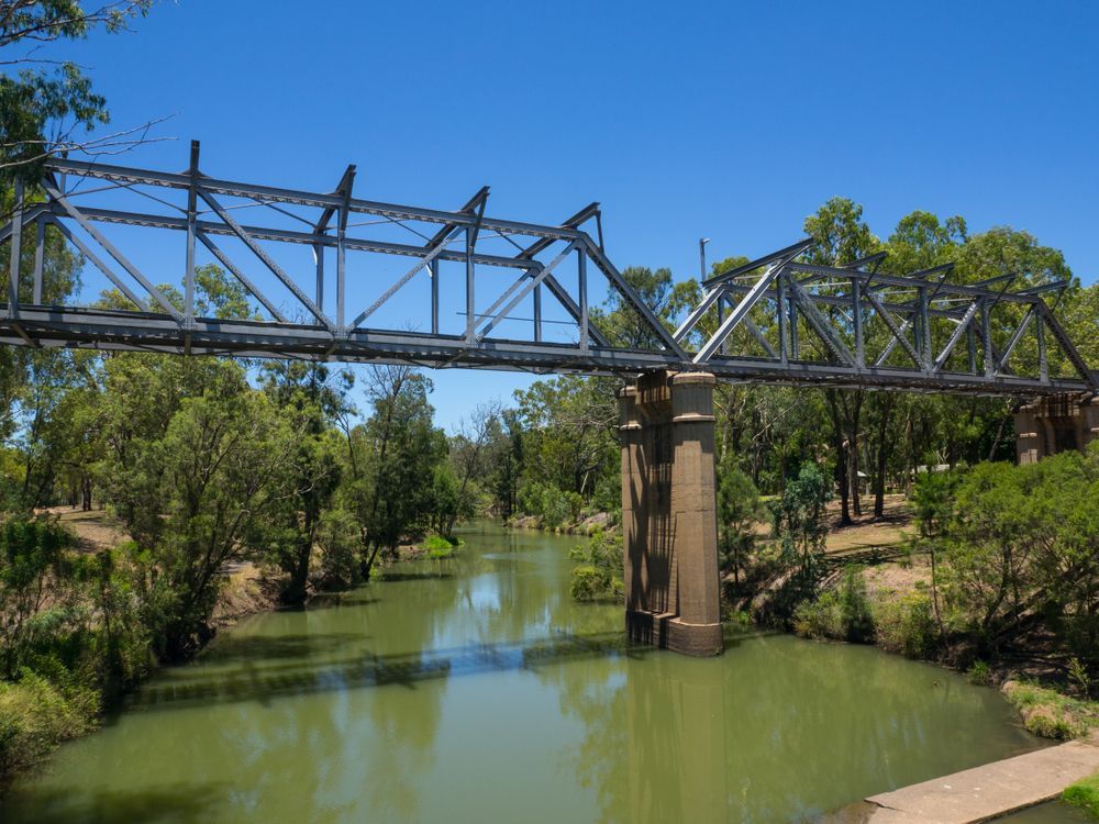 A Metal Truss Bridge Spans a Murky Green River — Australian Specialised Machinery Glass In Emerald, QLD