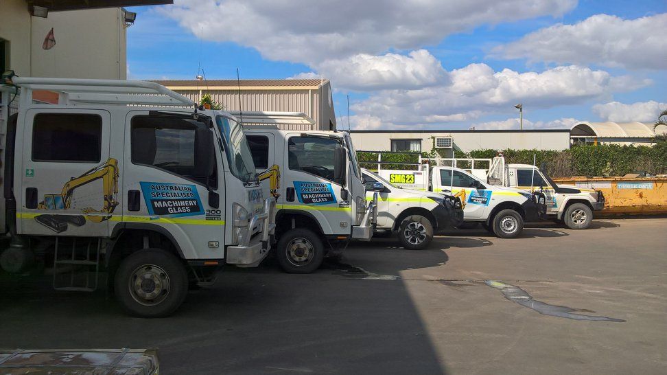 A Row Of Trucks Are Parked In A Parking Lot — Australian Specialised Machinery Glass In Emerald, QLD