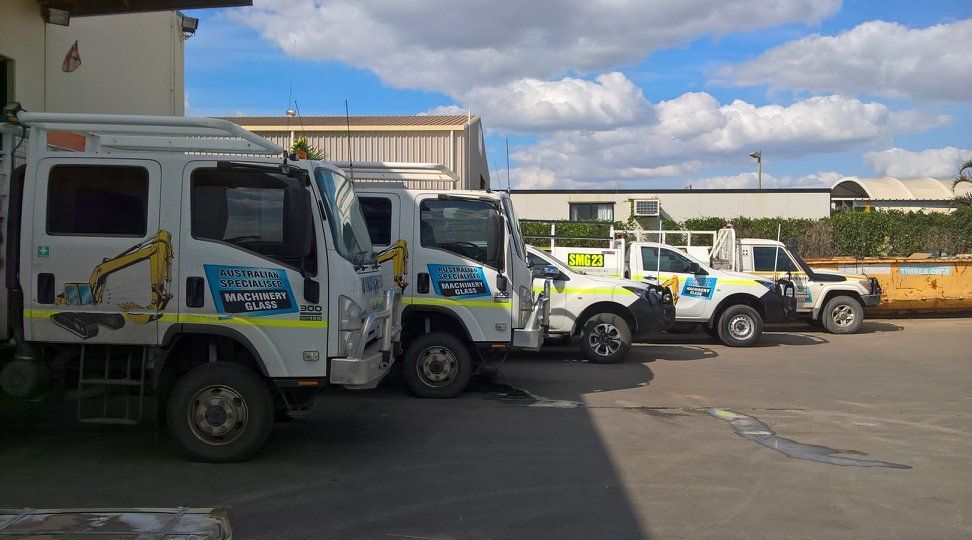 A White Truck With A Crane On Top Of It Is Parked In A Dirt Field — Australian Specialised Machinery Glass In Mount Louisa, QLD