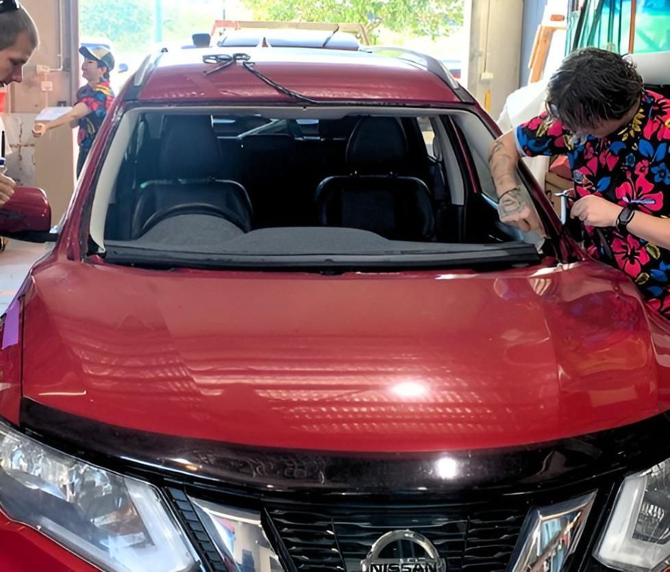 A Man Is Working On A Red Nissan Car In A Garage — Australian Specialised Machinery Glass In Mount Louisa, QLD