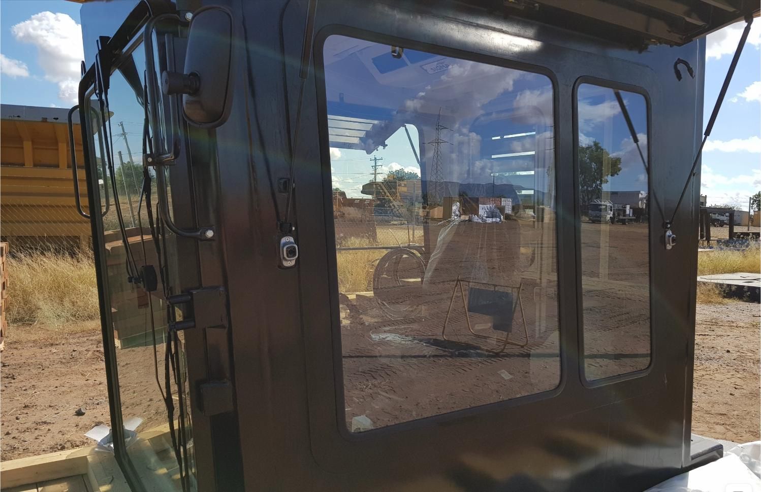 A Black Cab With Clear Glass Windows Is Sitting In A Dirt Field — Australian Specialised Machinery Glass In Mount Louisa, QLD