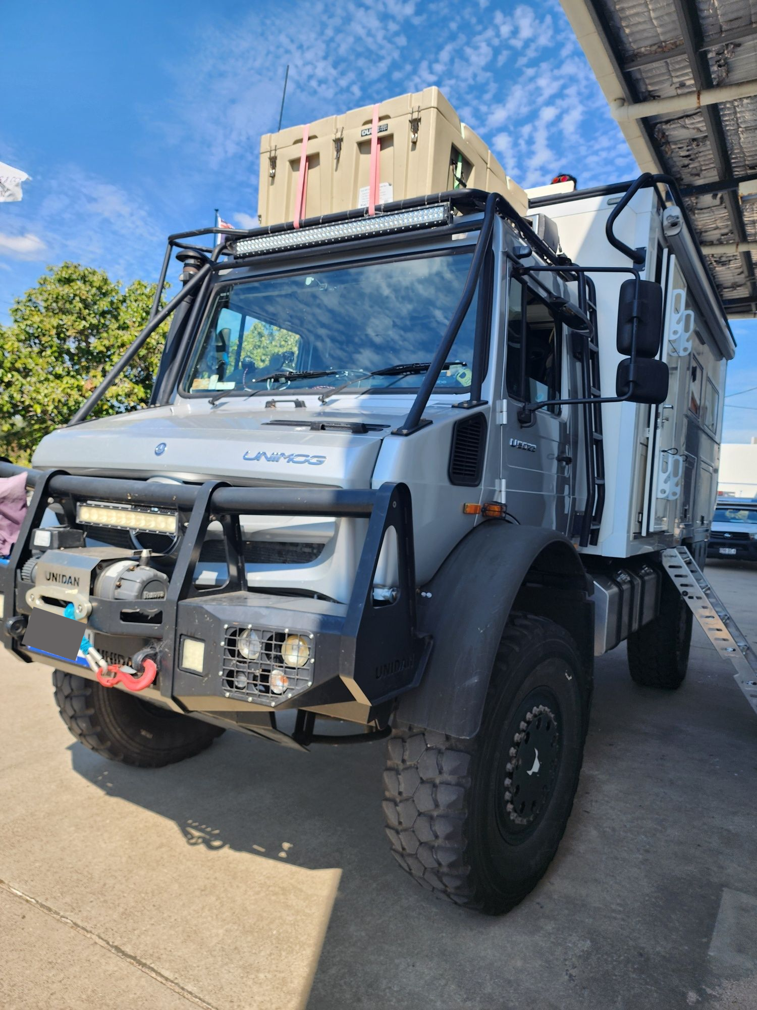 A Man Is Working On A Red Nissan Car In A Garage — Australian Specialised Machinery Glass In Mount Louisa, QLD