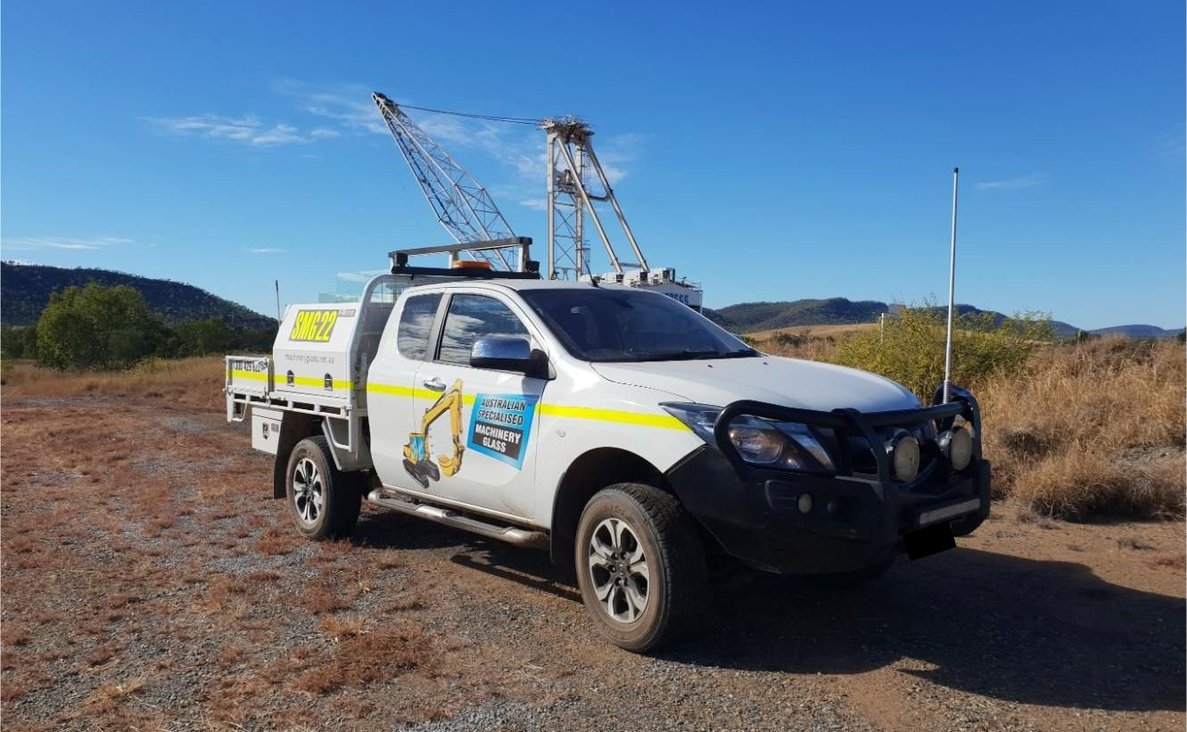 A White Truck With A Crane On Top Of It Is Parked In A Dirt Field — Australian Specialised Machinery Glass In Moranbah, QLD