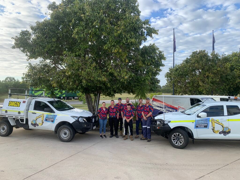 A Group Of People Are Posing For A Picture In Front Of Trucks — Australian Specialised Machinery Glass In Emerald, QLD