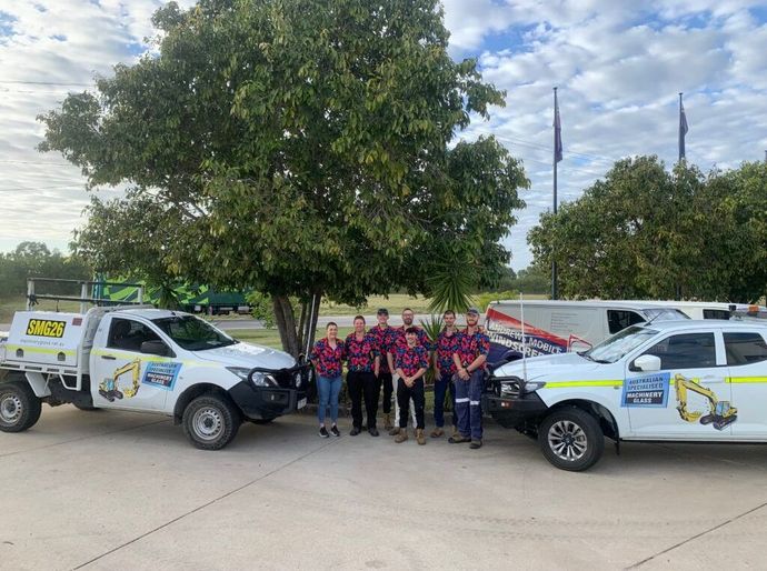 A Group Of People Are Posing For A Picture In Front Of Trucks — Australian Specialised Machinery Glass In Moranbah, QLD