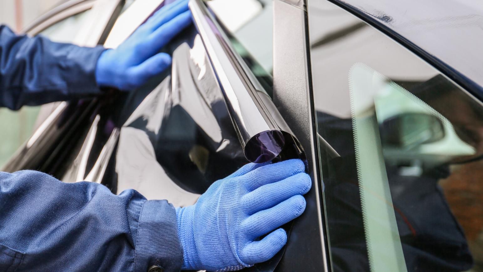 A Person Is Applying Tinted Glass To A Car Window — Australian Specialised Machinery Glass In Mount Louisa, QLD