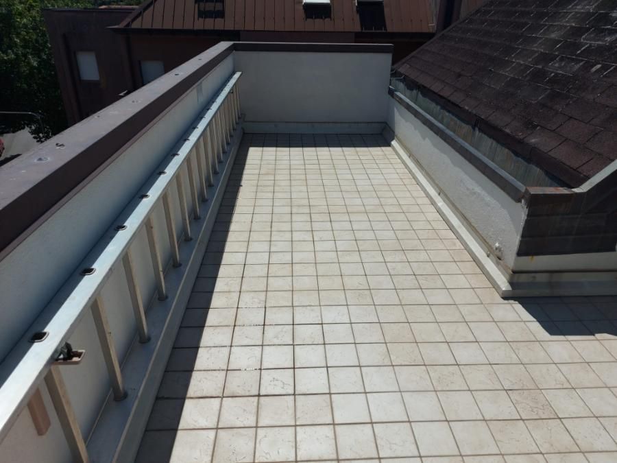 Un balcone con ringhiera in metallo e piastrelle bianche impermeabilizzazione