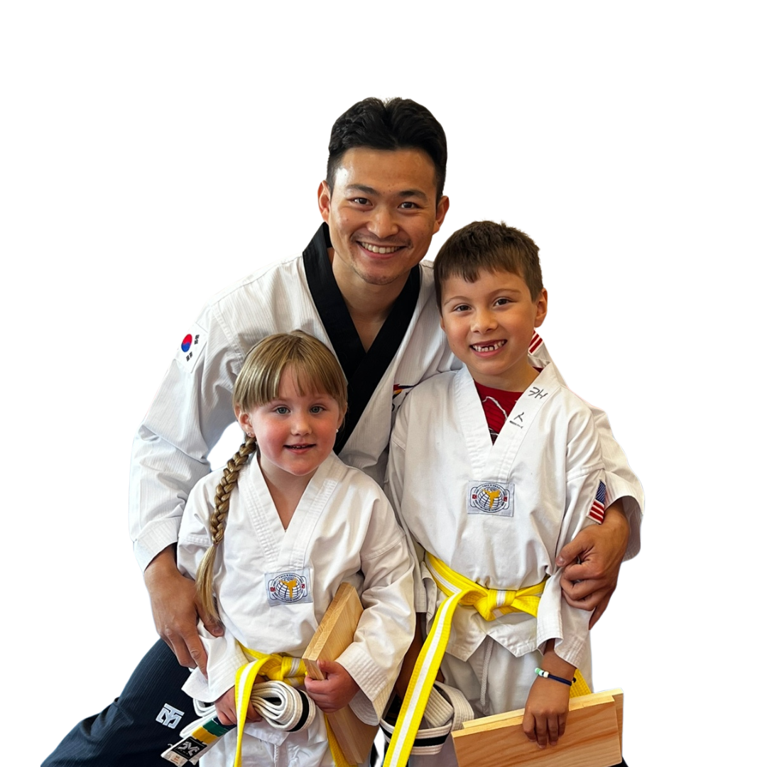 A group of kids in karate uniforms are sitting on the floor drinking water