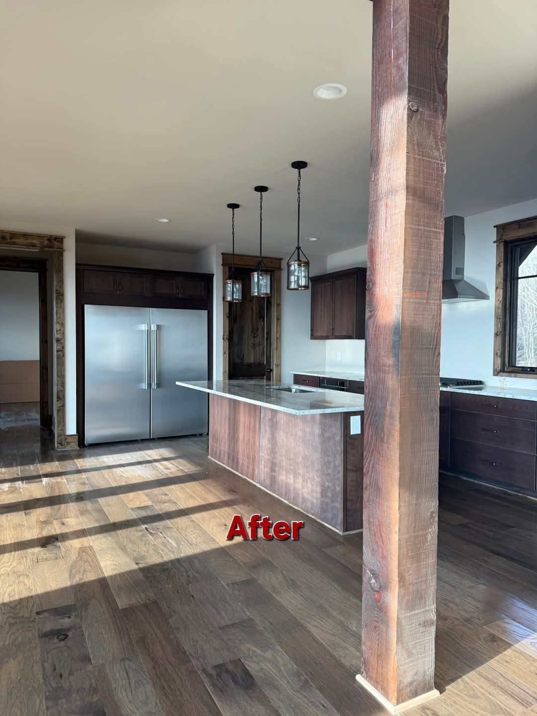 Newly remodeled kitchen with wood floors, island, stainless steel appliances, and a rustic wooden beam.