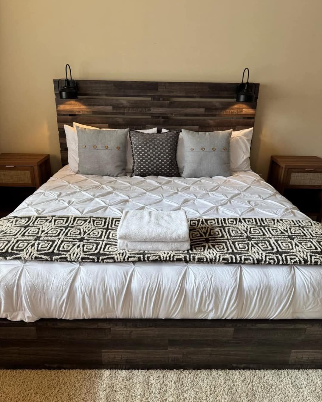 A bed with a wooden headboard and pillows in a bedroom.