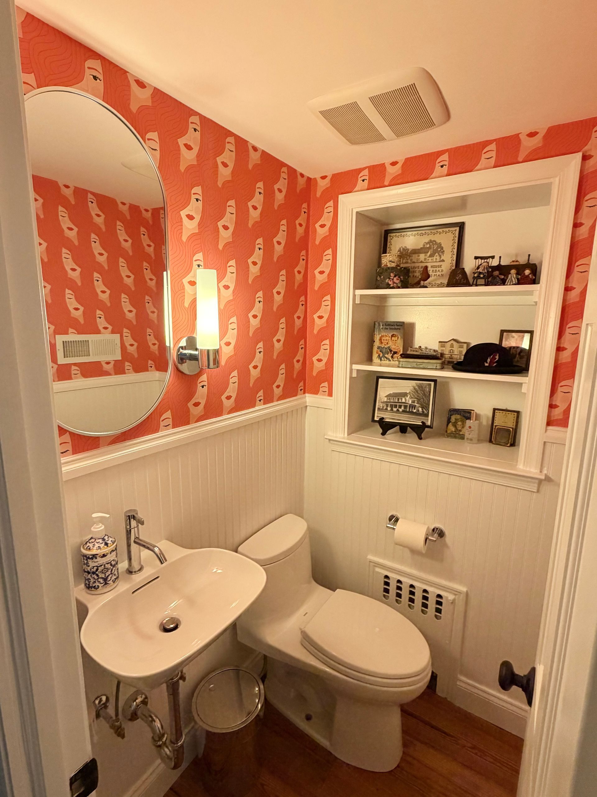 A bathroom featuring a shower with a black-framed, frosted glass door, white tiled walls, and patterned floor tiles.