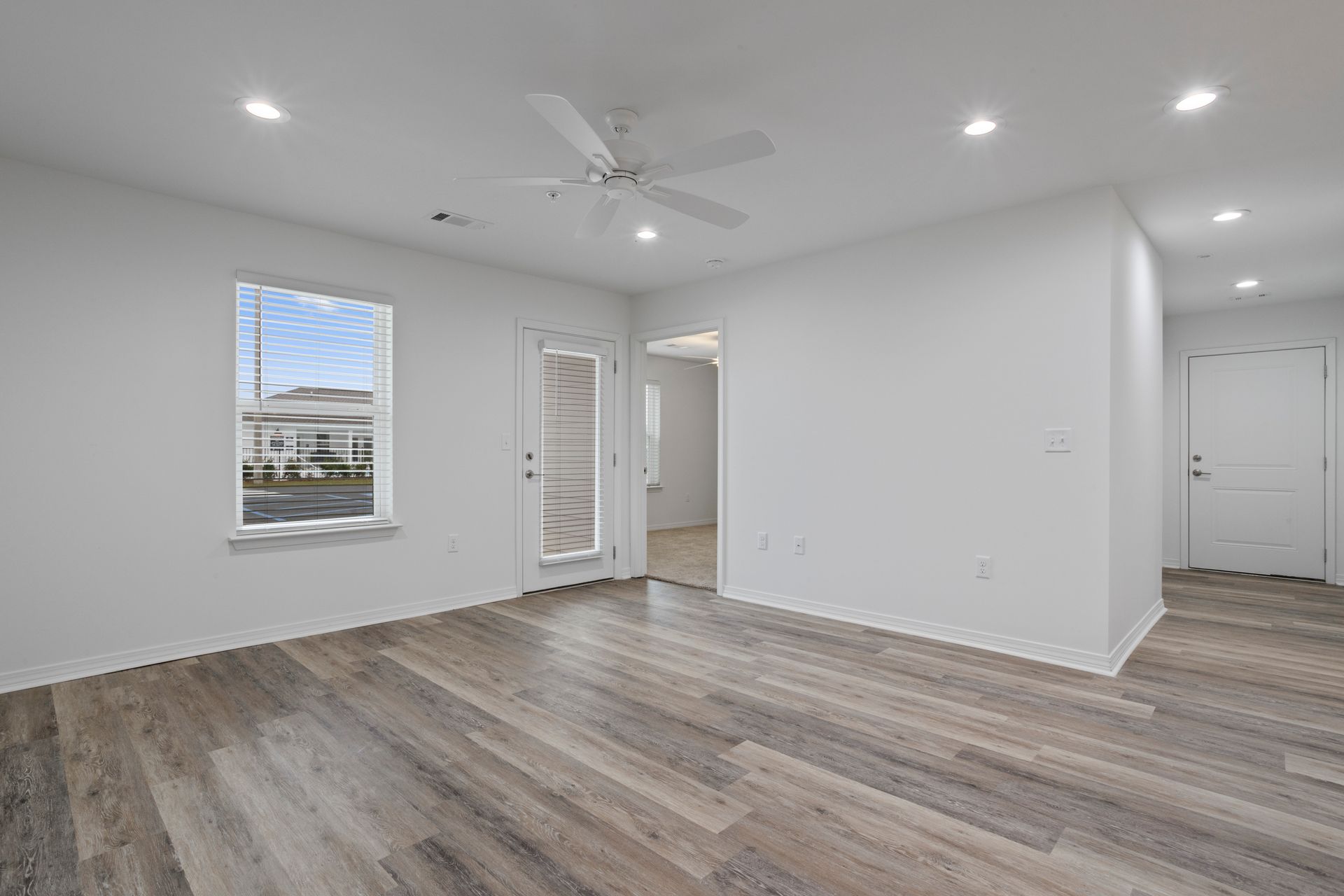 Photo of a living room and there is a hallway in the background