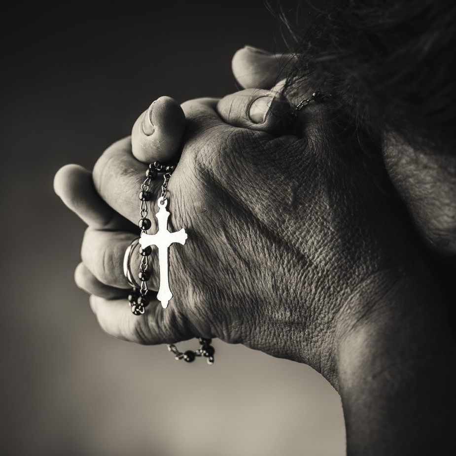 A person is praying with a rosary in their hands