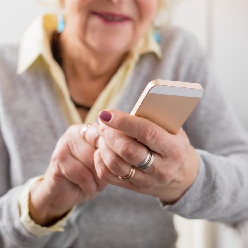 An older woman is holding a cell phone in her hand.