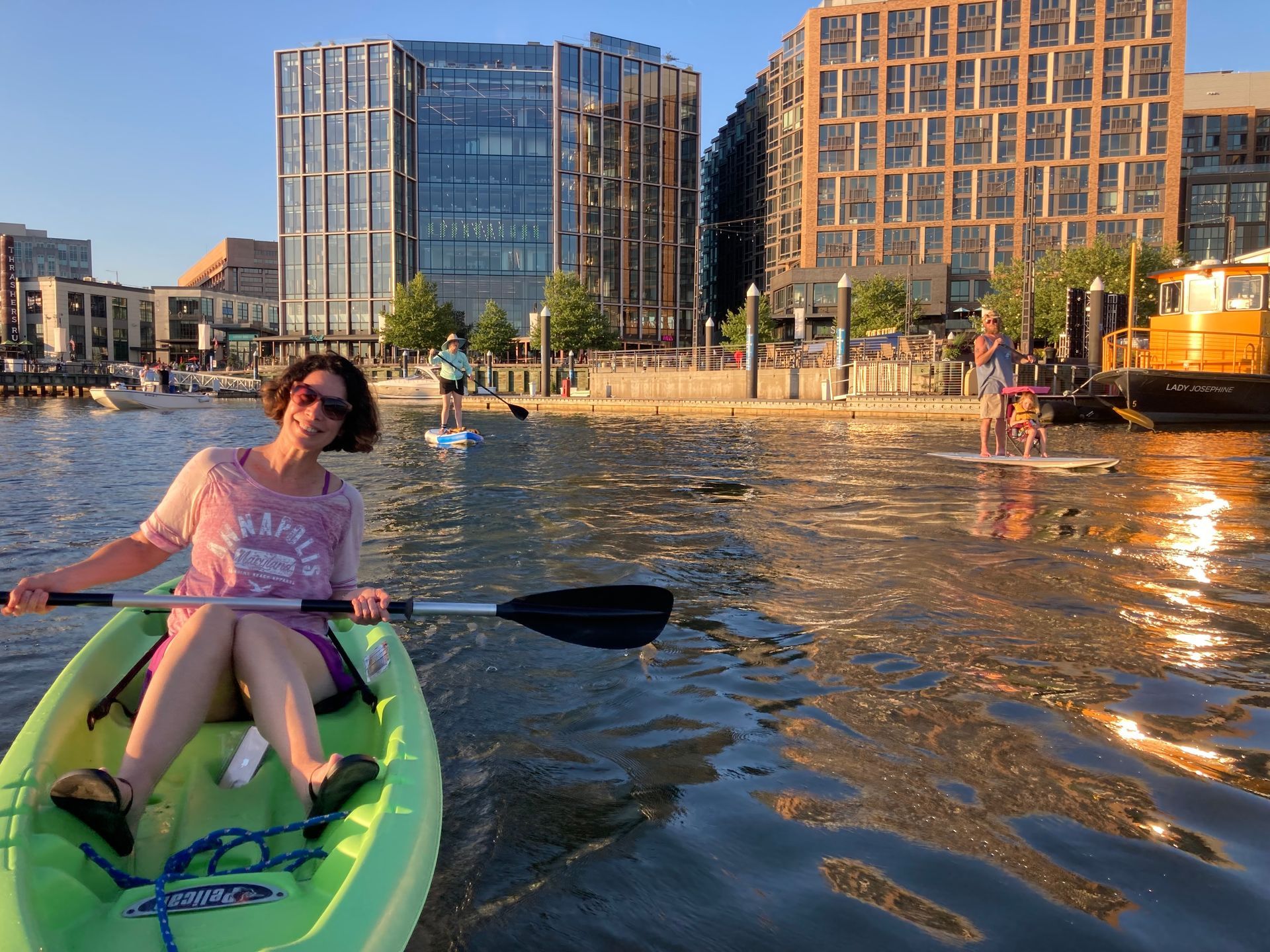 Woman on a green kayak with the Wharf DC in the background | Luxury homes in DC