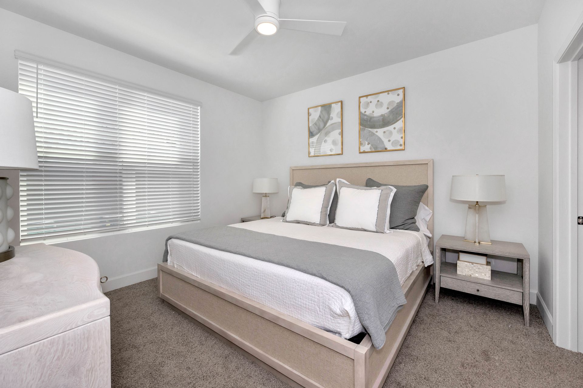 Stylish bedroom with a gray and white color scheme, featuring a bed, side tables, and artwork.