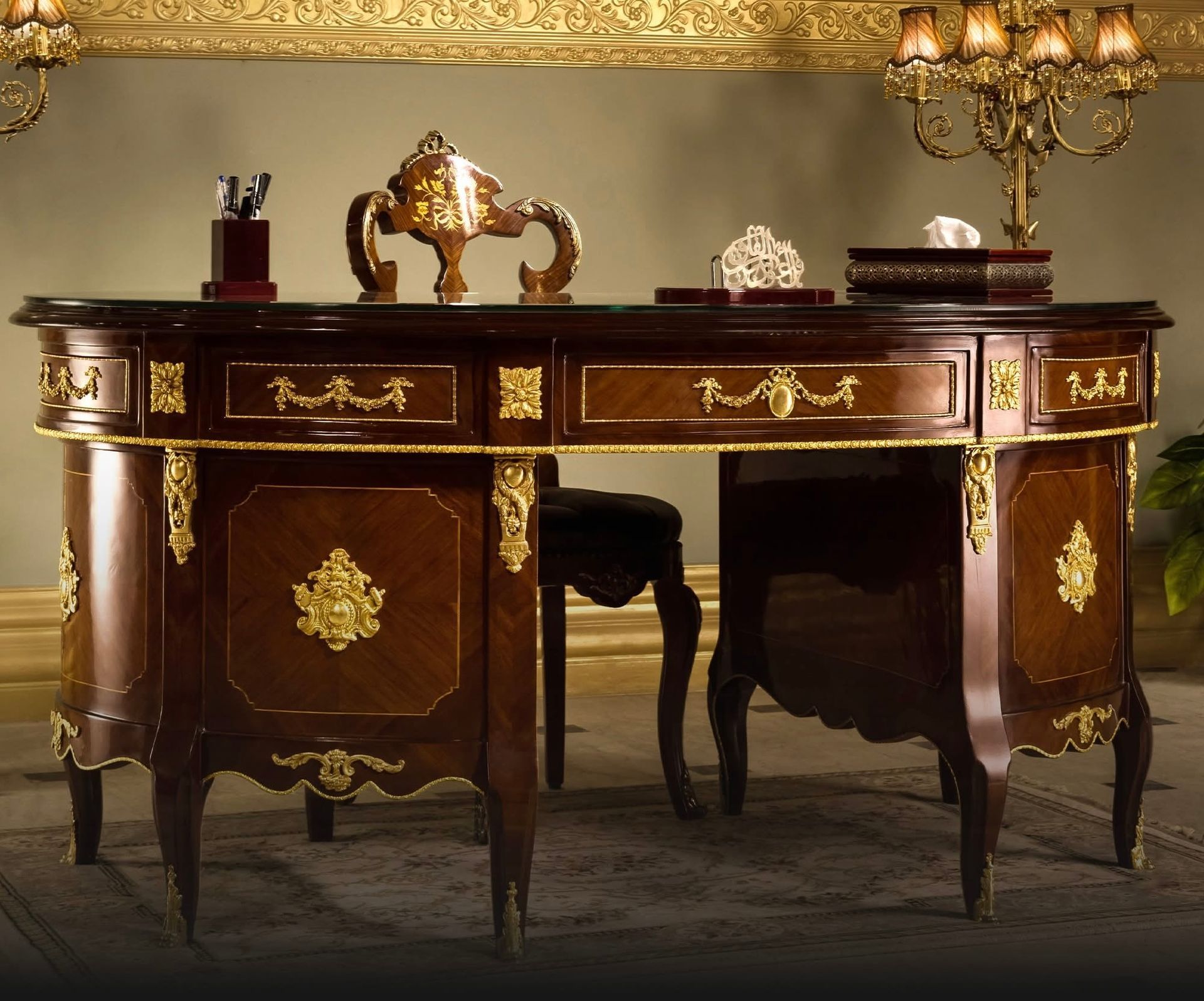 A wooden desk with gold trim and a lamp on top