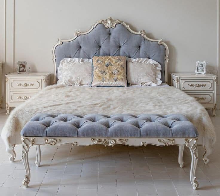 A bed with a blue bench underneath it in a bedroom.