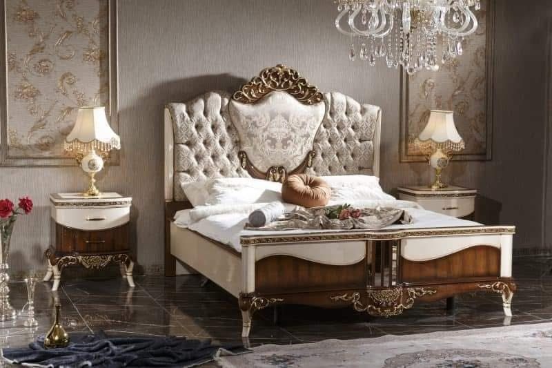 A bedroom with a bed , nightstands , lamps and a chandelier.